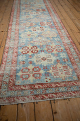 Long angle view of a distressed antique Persian runner showing its bold geometric pattern.