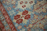 Detailed texture of a distressed antique rug with cherry red and ivory serrated medallions on a powder blue ground.