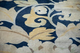 Hand knotted Tibetan carpet detail with sprawling cobalt blue, beige, and saffron floral palmettes.