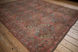 Distressed Ersari carpet with repeating faded guls and geometric serrated border.