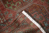 Distressed raspberry red and blue pattern with secured white side binding on an Ersari rug.
