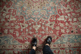 Distressed red and blue floral pattern on a vintage Khoy carpet with visible worn pile.