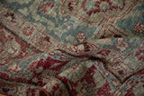 Folded vintage distressed Khoy carpet, revealing worn red, teal, and beige motifs.