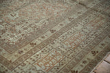 A close-up of the signature cartouche border on an antique Tabriz carpet in sandalwood tones.