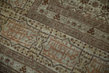 Detailed view of the signature cartouche border with copper tones on an antique Tabriz rug.