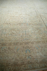 Distressed Tabriz carpet showing faded scrolling vines, floral motifs, and soft blue.