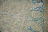 Distressed Persian Tabriz carpet detail: worn scrolling vines in faded ivory, blue, and sand.