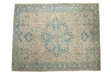 Vintage distressed Persian Heriz carpet with a large blue medallion on a sand-colored field with floral details.