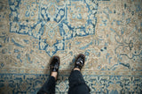 Low-pile texture of a distressed vintage Heriz carpet with cobalt blue, sand, and cream floral motifs.