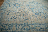 Low, even pile of a distressed Persian Heriz showing stylized floral motifs in blue, sand, and cream.