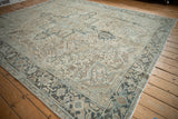 Corner of distressed Heriz rug showing muted teal Samovar Turtle border and worn floral field.