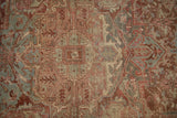 Distressed Heriz carpet with geometric arabesque and floral motifs in dusty red and muted silver tones.