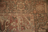 Distressed Heriz carpet pile, showing mostly even wear with muted reds and oxidized silver tones.