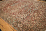 Distressed Persian Heriz rug corner: faded red, beige, and silver floral border details.