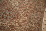 Distressed vintage Heriz rug close-up showing faded red, beige, and light blue geometric motifs.