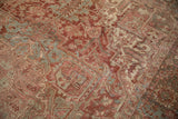 Close-up of distressed vintage Heriz rug, time-softened reds, muted silver, geometric patterns.
