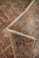 Vintage distressed Heriz rug folded, revealing worn pile, woven foundation, and light fringe.