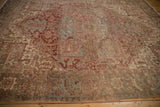Distressed vintage Heriz carpet showing floral border with serrated leaves, dusty red, silver tones.