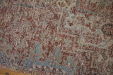 Distressed Heriz carpet with worn pile, revealing softened red, silver, and beige pattern detail.