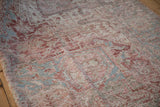 Distressed vintage Heriz carpet's worn pile texture, with faded dusty red and light blue.