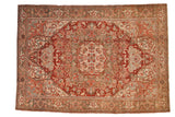 Distressed vintage Heriz carpet with oversized cherry red medallion and intricate floral vines.