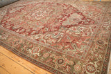 Vintage distressed Heriz carpet corner, revealing Herati border and arabesque spandrel in faded red and olive.