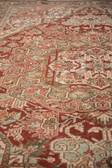 Distressed Heriz carpet texture with faded cherry red and dusty olive geometric patterns.