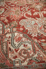 Distressed Heriz carpet pile featuring cherry red, ivory, blue, and green geometric motifs.