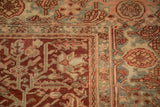 Corner of distressed vintage Heriz carpet showing intricate Herati and vine patterns, time-softened burgundy and teal.