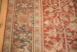 Distressed vintage Heriz rug pile showing red, teal, beige floral patterns and even wear.