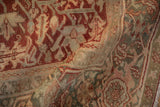 Distressed vintage Heriz carpet detail, highlighting hand-knotted pile and deep red, dusty teal floral motifs.