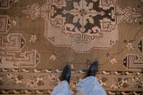 Distressed vintage Kars carpet showing coffee brown, dusty mauve, and geometric spandrel patterns.