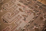 Distressed Kars carpet showing dusty mauve floral border and coffee brown hook and latch motifs.