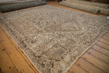 Distressed Heriz carpet corner with heavy abrashes and geometric patterns in brown and beige.