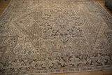 Distressed vintage Heriz rug, geometric medallion pattern in muted beige, brown, and soft blue.