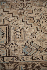 Vintage Heriz rug close-up: geometric design with worn knot heads in beige and brown.