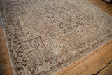 Distressed Heriz carpet border, showing geometric motifs in brown and pale blue tones.
