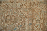 Close-up: Distressed vintage Heriz carpet's geometric Karaja pattern in browns, blue, with faint foundation showing.