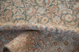 A vintage Tabriz rug folded to show its low pile and soft terracotta and blue pattern.