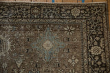 Corner of a vintage Heriz carpet showing the dark floral border and low pile with even wear.