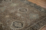 Angled view of a vintage Heriz carpet's geometric field and dark floral border.