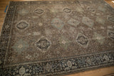 Angled view of a vintage Heriz carpet showing rows of stylized Karaja medallions on an abrased brown field.
