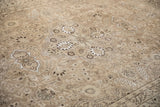 Floral medallion with artificial silk highlights on a distressed beige and brown vintage Tabriz rug.