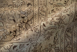 A distressed Tabriz rug curled to show the low pile, knot heads, and brown floral arabesque.