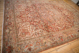 An overall view of a vintage Ahar carpet's distressed, sprawling floral design and borders.