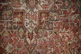 Distressed Heriz rug's textured pile in dusty raspberry, sand, and teal geometric pattern.
