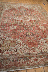 Close-up of distressed Heriz carpet's corner, showing geometric border and worn fringe.