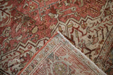 Distressed Heriz carpet's folded corner reveals faded patterns and woven reverse with color run.