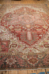 Distressed vintage Heriz rug border with geometric and primitive floral motifs in red, charcoal, gold.
