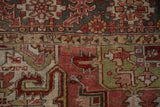 Distressed vintage Heriz rug detail with geometric serrated patterns, brick red, and green.